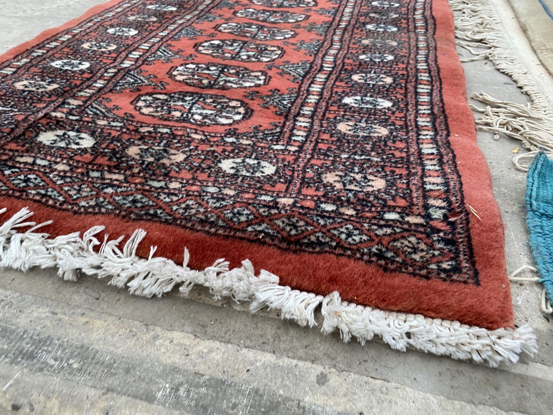 A SMALL RED PATTERNED FRINGED RUG - Bild 2 aus 2