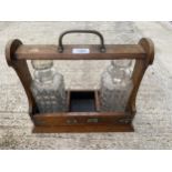 A VINTAGE OAK TANTALUS DECANTER HOLDER WITH TWO GLASS DECANTERS AND SILVER PLATE DETAIL
