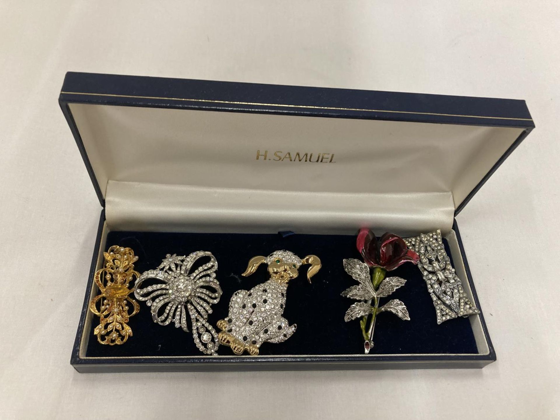 A BOX CONTAINING FIVE COSTUME JEWELLERY BROOCHES TO INCLUDE A DOG, ROSE, ETC