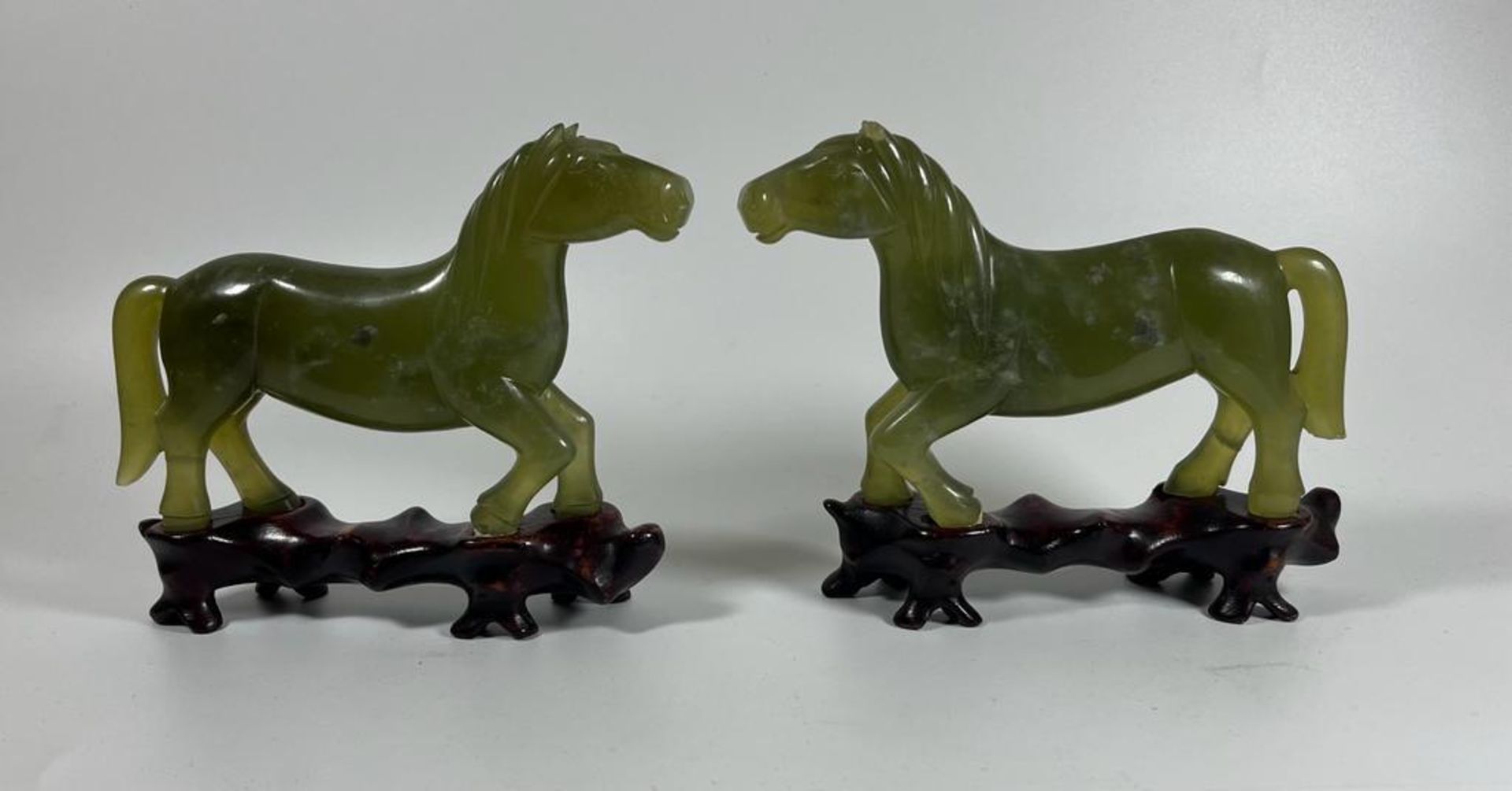 A PAIR OF JADE STYLE HARDSTONE HORSES ON CARVED WOODEN BASES, HEIGHT 12 CM