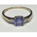A 9 CARAT GOLD RING WITH A PURPLE GEMSTONE SURROUNDED BY TWO DIAMONDS SIZE R/S
