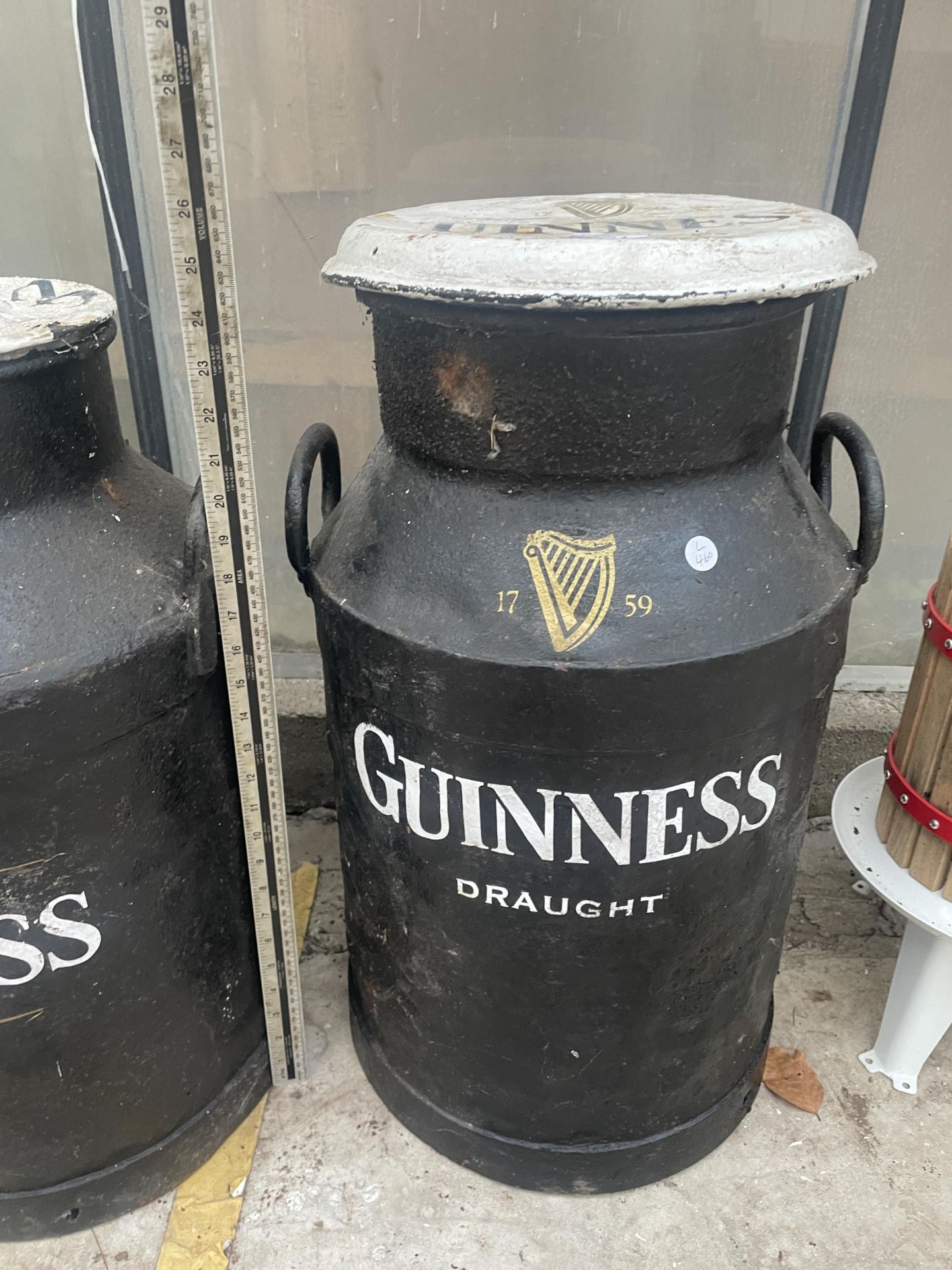 A DECORATIVE METAL MILK CHURN WITH LID AND GUINNESS DETAILING