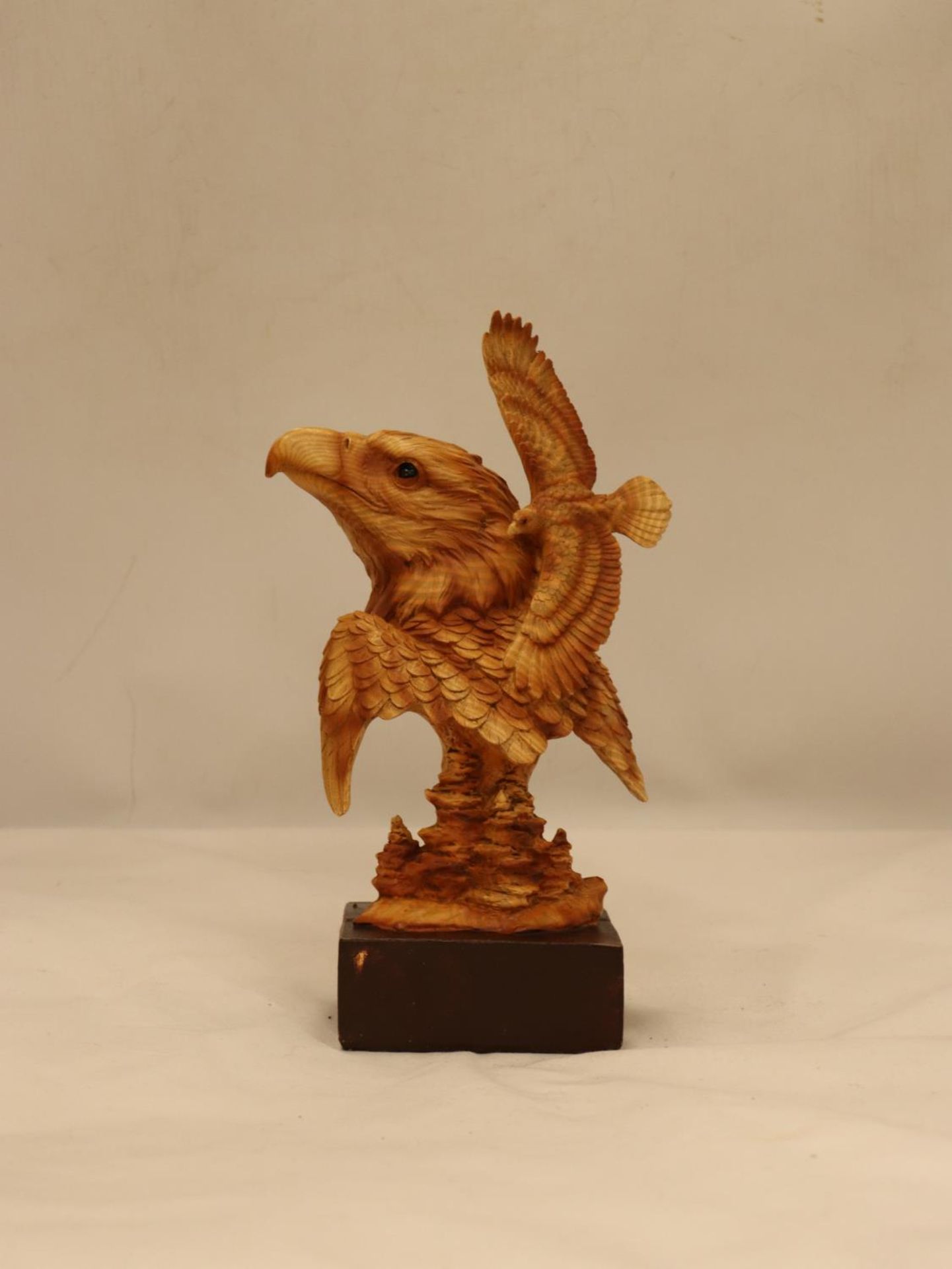 A WOODEN CARVED EAGLE'S HEAD ON A PLINTH, HEIGHT 25CM