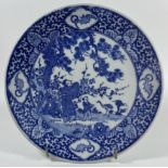 A JAPANESE BLUE AND WHITE POTTERY CHARGER PLATE WITH FIGURES IN GARDEN DESIGN, DIAMETER 22 CM