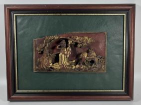 A CHINESE LACQUERED AND GILT CARVED WOODEN PANEL, ON LATER GREEN LEATHER MOUNT AND WOODEN FRAME,