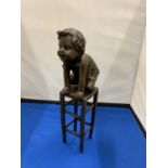 A BRONZE MODEL OF A CHILD KNEELING ON A STOOL SIGNED