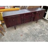 A RETRO 'ENSIGN' STAINED ELM SIDEBOARD ENCLOSING FOUR DRAWERS AND TWO CUPBOARDS, 70" WIDE