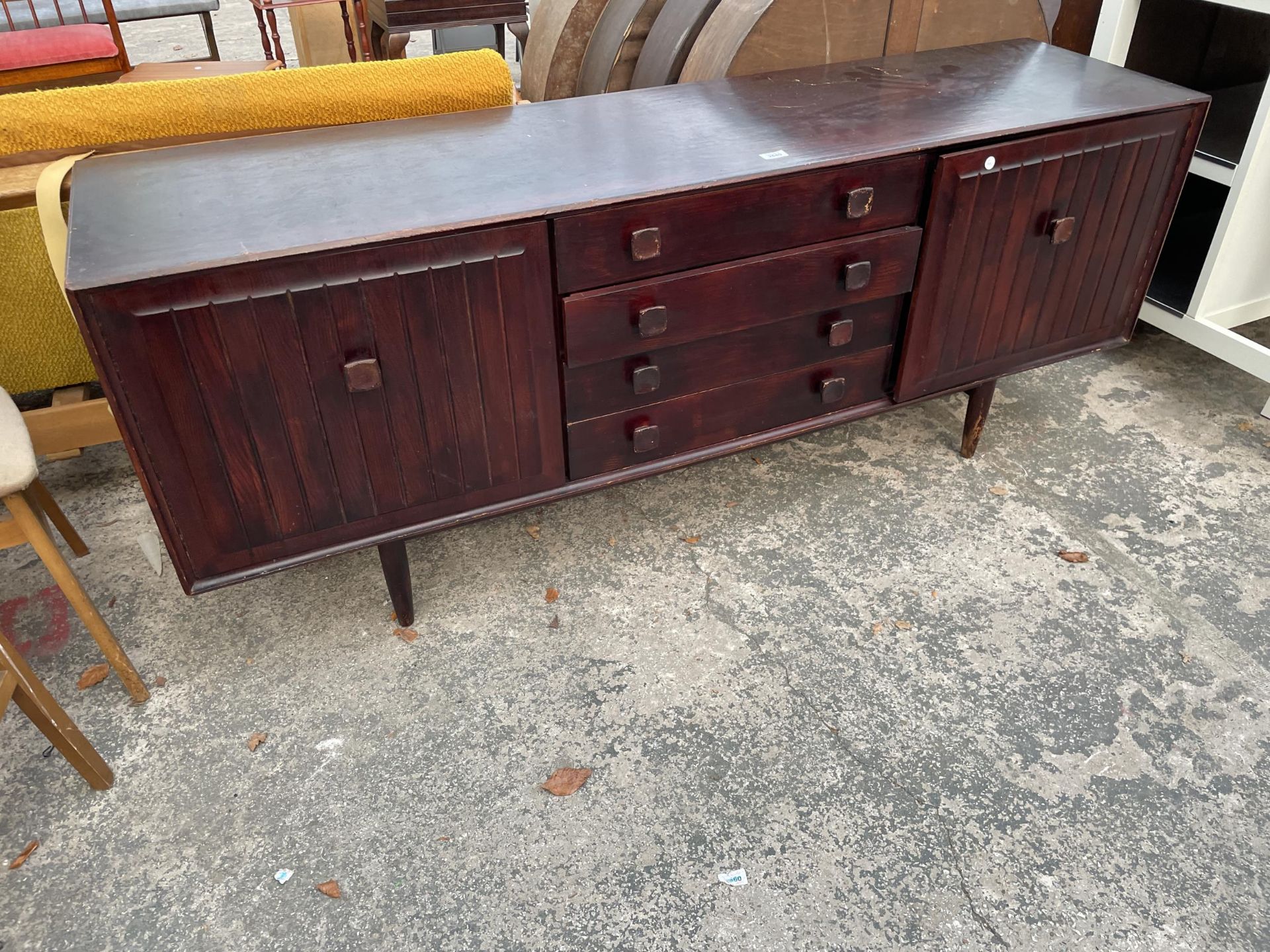 A RETRO 'ENSIGN' STAINED ELM SIDEBOARD ENCLOSING FOUR DRAWERS AND TWO CUPBOARDS, 70" WIDE