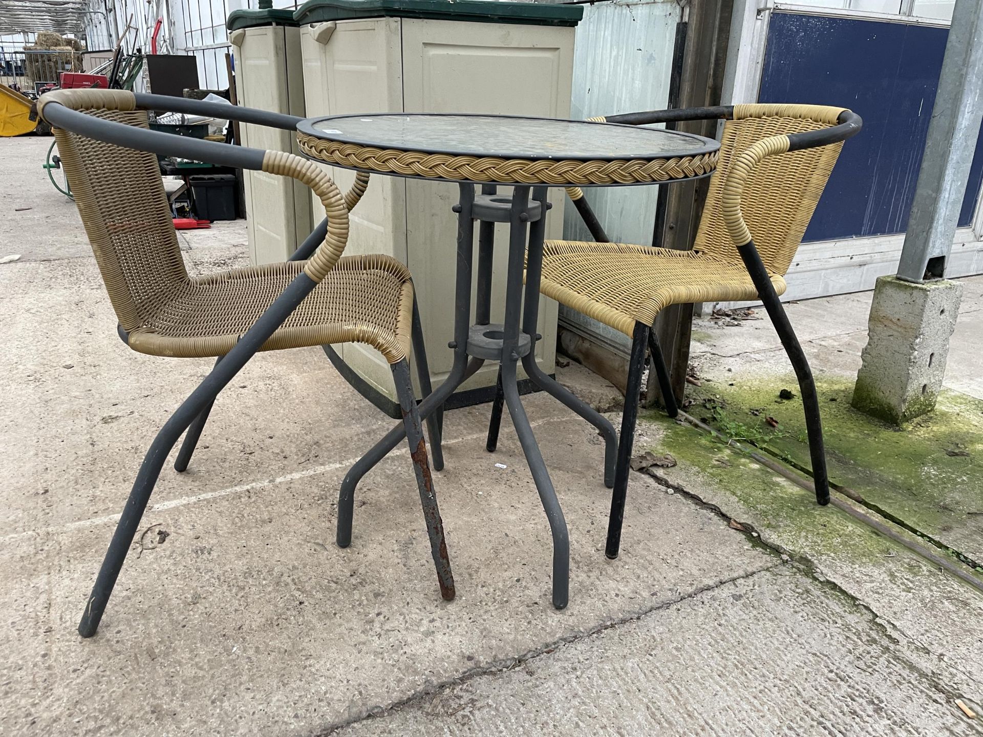 A GLASS TOPPED BISTRO TABLE AND TWO RATTAN EFFECT CHAIRS - Image 2 of 3