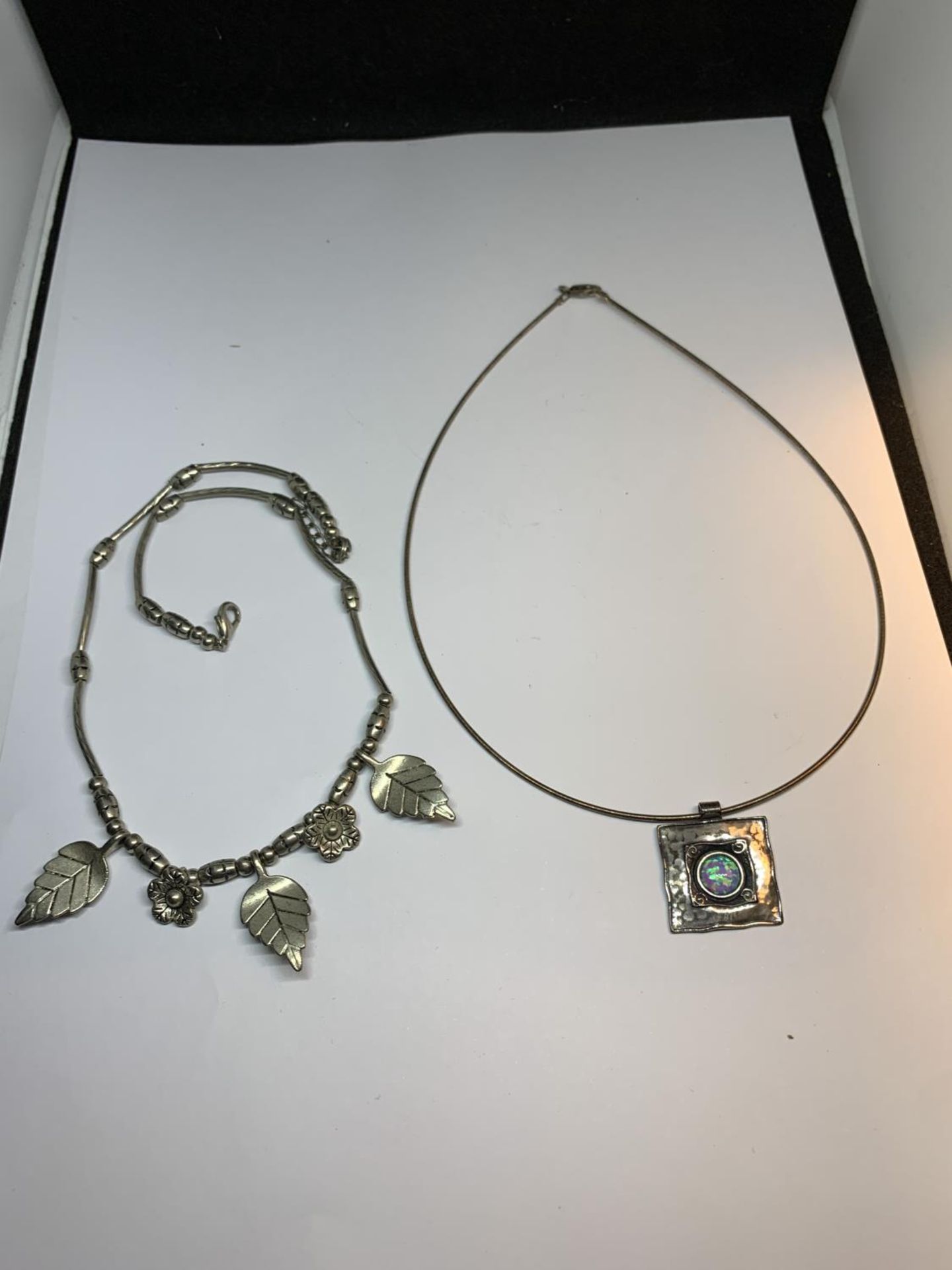 TWO SILVER NECKLACES ONE WITH LEAVES AND FLOWERS AND ONE WITH A PENDANT