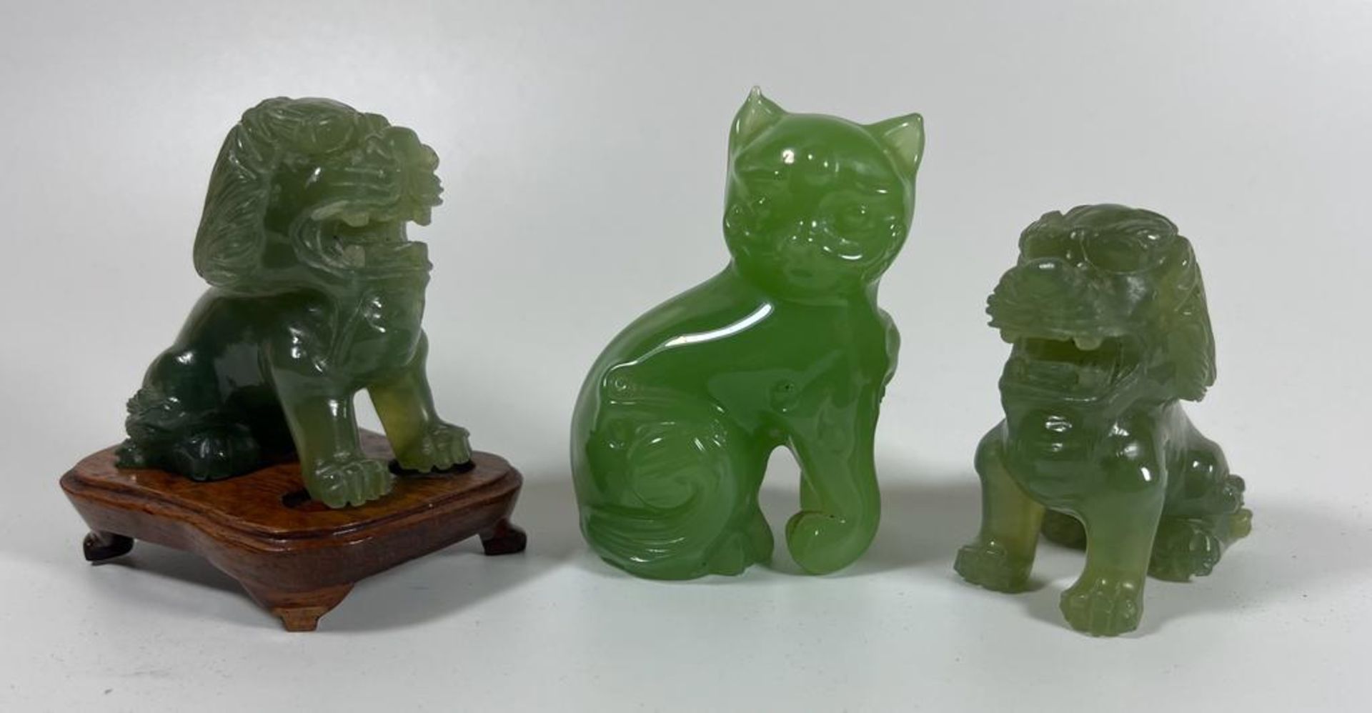 THREE JADE STYLE HARDSTONE ITEMS - PAIR OF CARVED FOO DOGS, ONE ON WOODEN BASE AND A CAT, HEIGHT 7