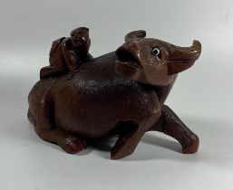 A CHINESE CARVED HARDWOOD FIGURE OF AN OX WITH FIGURE ON ITS BACK, WITH BONE EYES, HEIGHT 12 CM