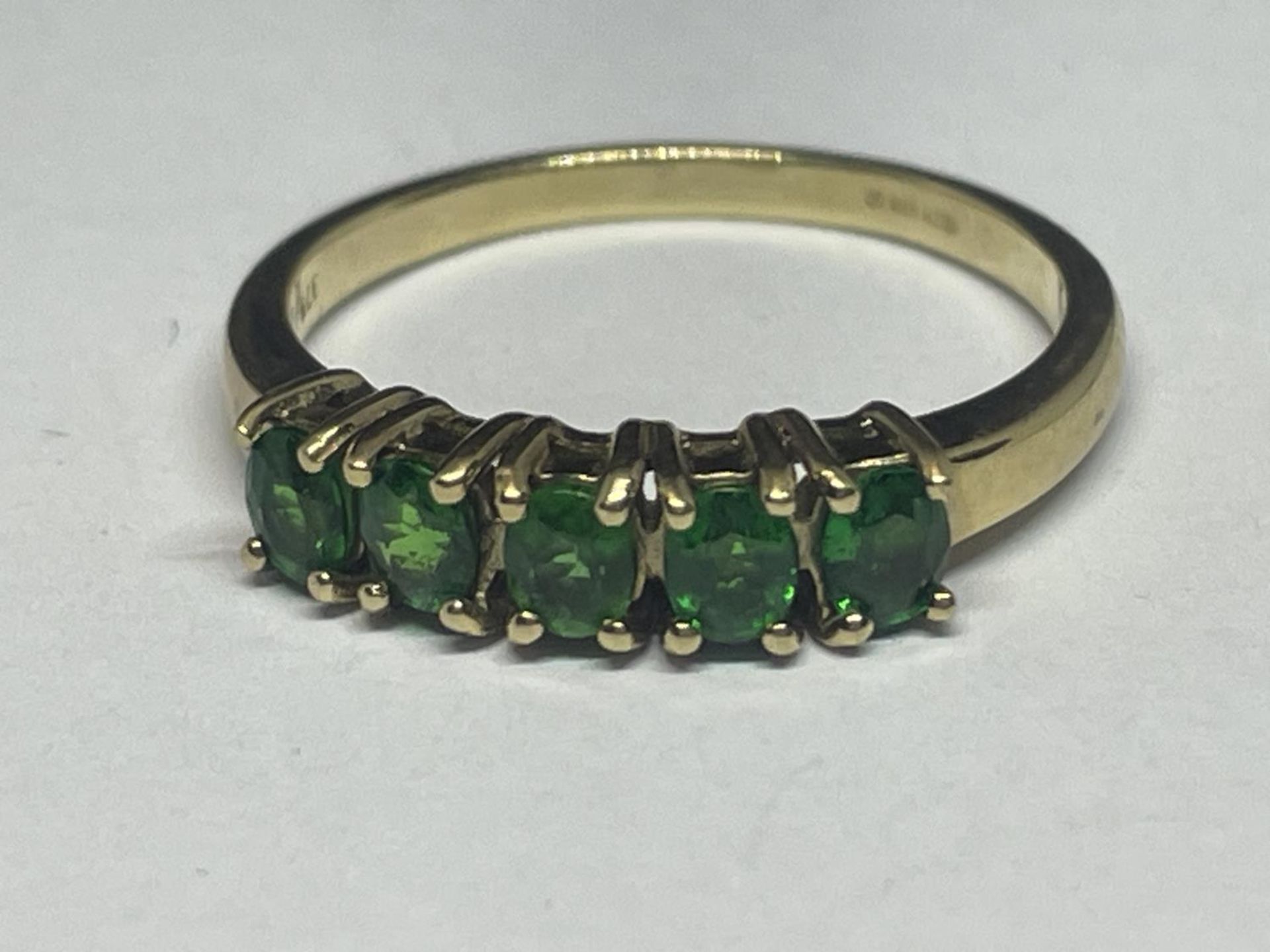 A 9 CARAT GOLD RING WITH FIVE IN LINE EMERALDS SIZE N/0