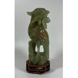A CARVED JADE STYLE HARDSTONE MODEL OF A BIRD ON A CARVED WOODEN BASE, HEIGHT 20 CM