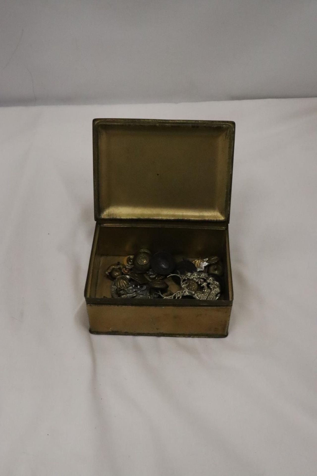 A BRASS BOX CONTAINING MILITARY BUTTONS AND BADGES