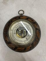 A CIRCULAR BAROMETER WITH A CARVED FRAME