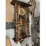 A CARVED WALNUT VIENNA WALL CLOCK WITH ROMAN NUMERALS AND PENDULUM
