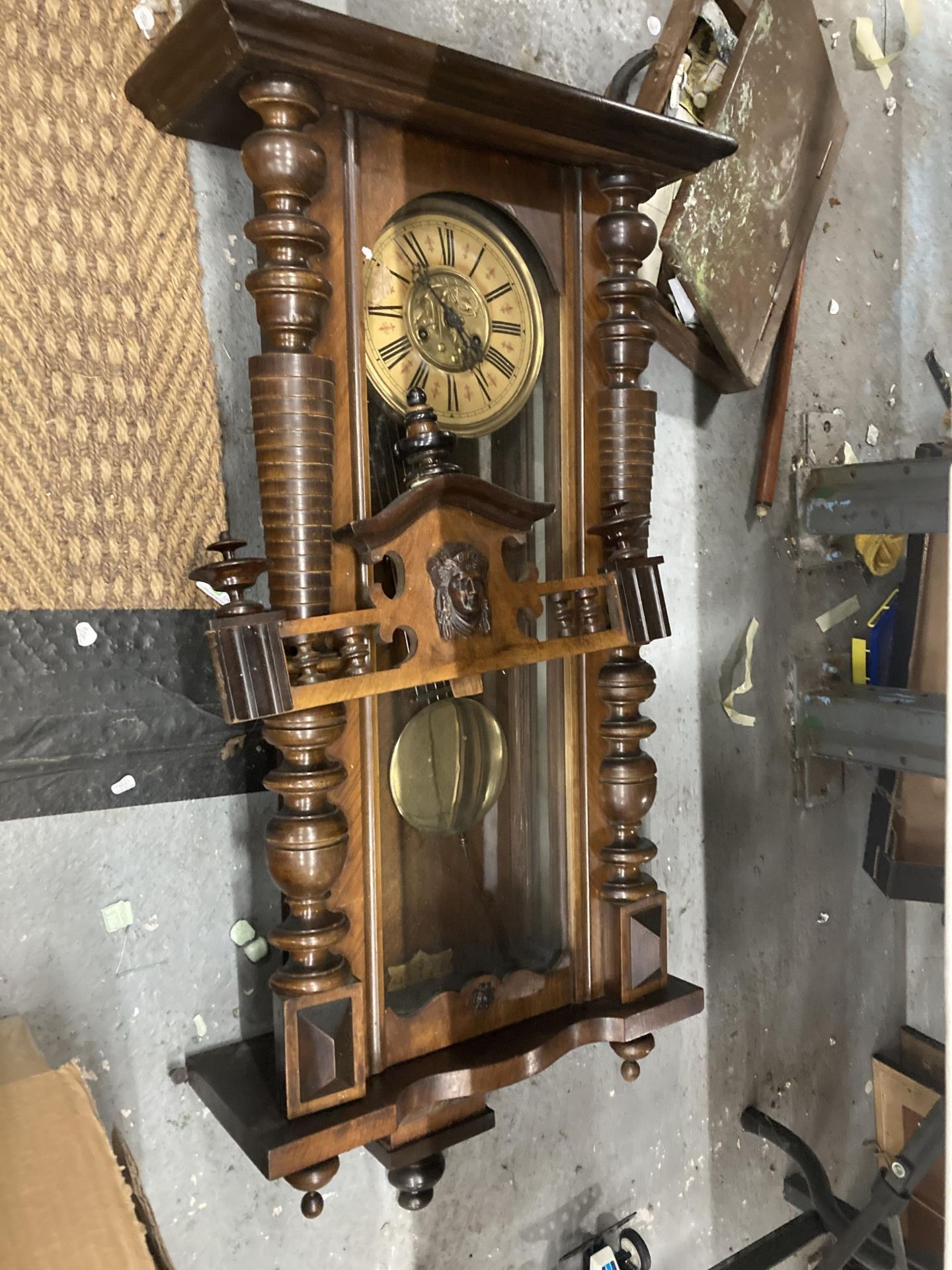 A CARVED WALNUT VIENNA WALL CLOCK WITH ROMAN NUMERALS AND PENDULUM