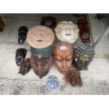 AN ASSORTMENT OF TREEN CARVED TRIBAL MASKS AND FURTHER CERAMIC MASKS ETC