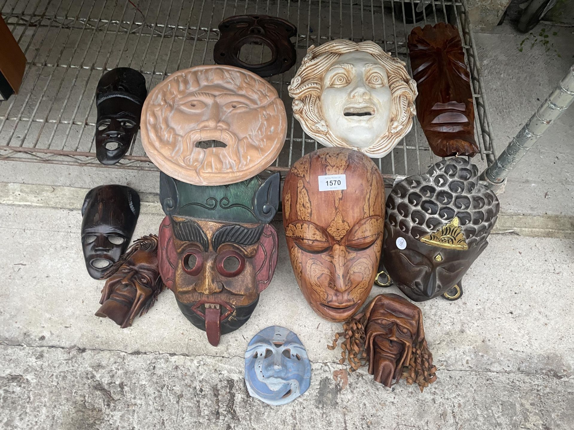 AN ASSORTMENT OF TREEN CARVED TRIBAL MASKS AND FURTHER CERAMIC MASKS ETC