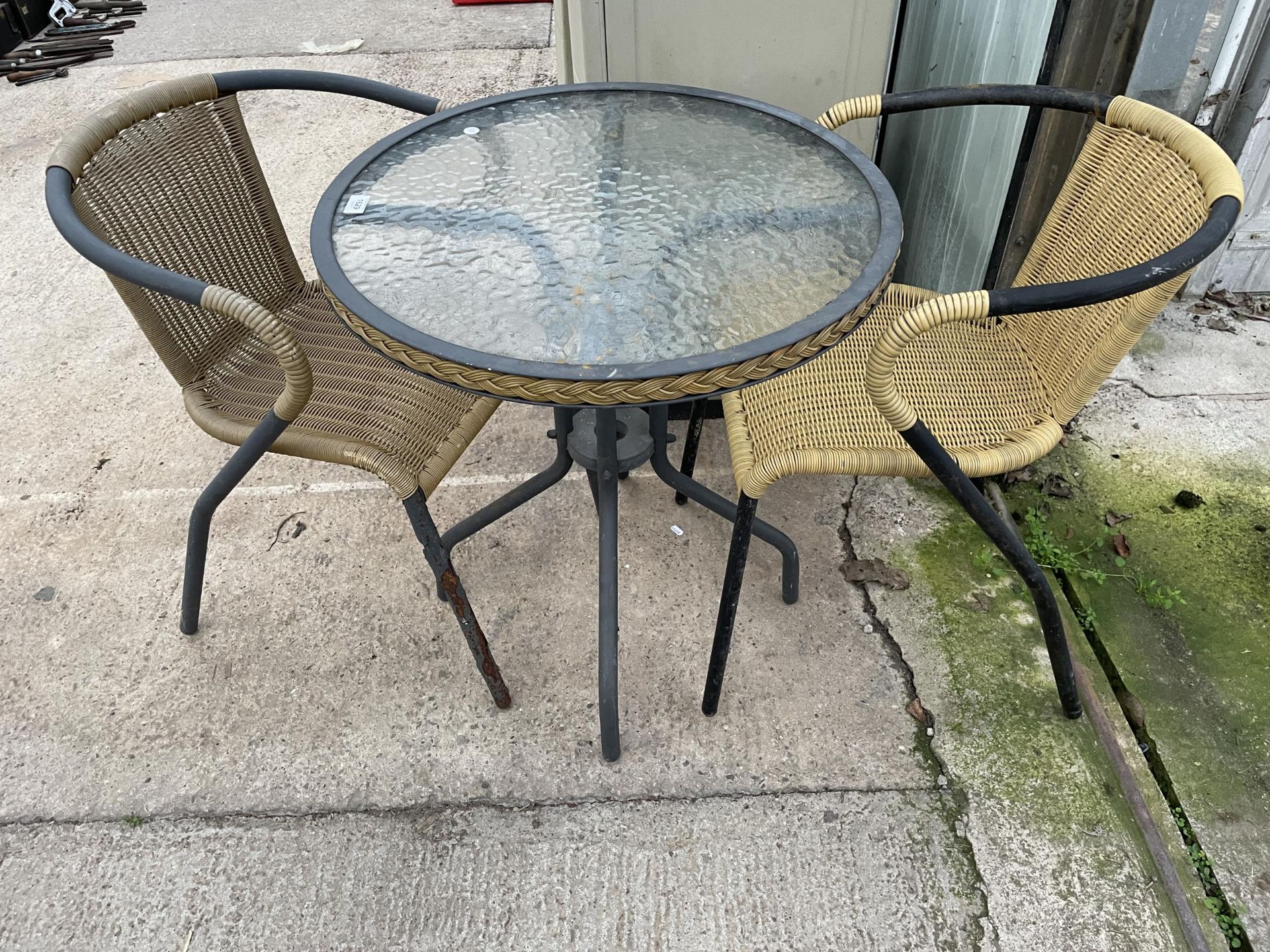 A GLASS TOPPED BISTRO TABLE AND TWO RATTAN EFFECT CHAIRS