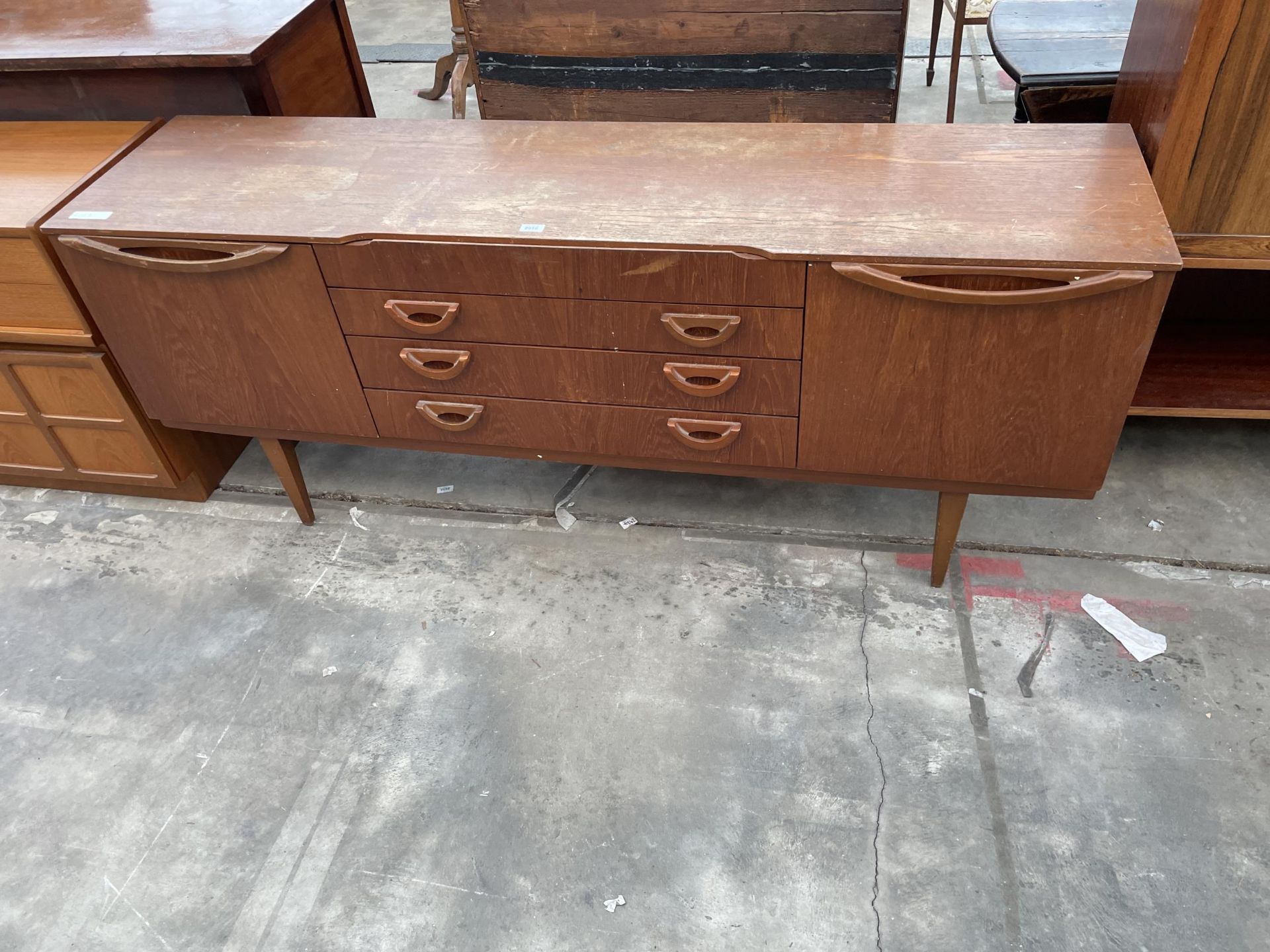 A RETRO TEAK BEAUTILITY SIDEBOARD ENCLOSING FOUR DRAWERS AND TWO CUPBOARDS, 72" WIDE