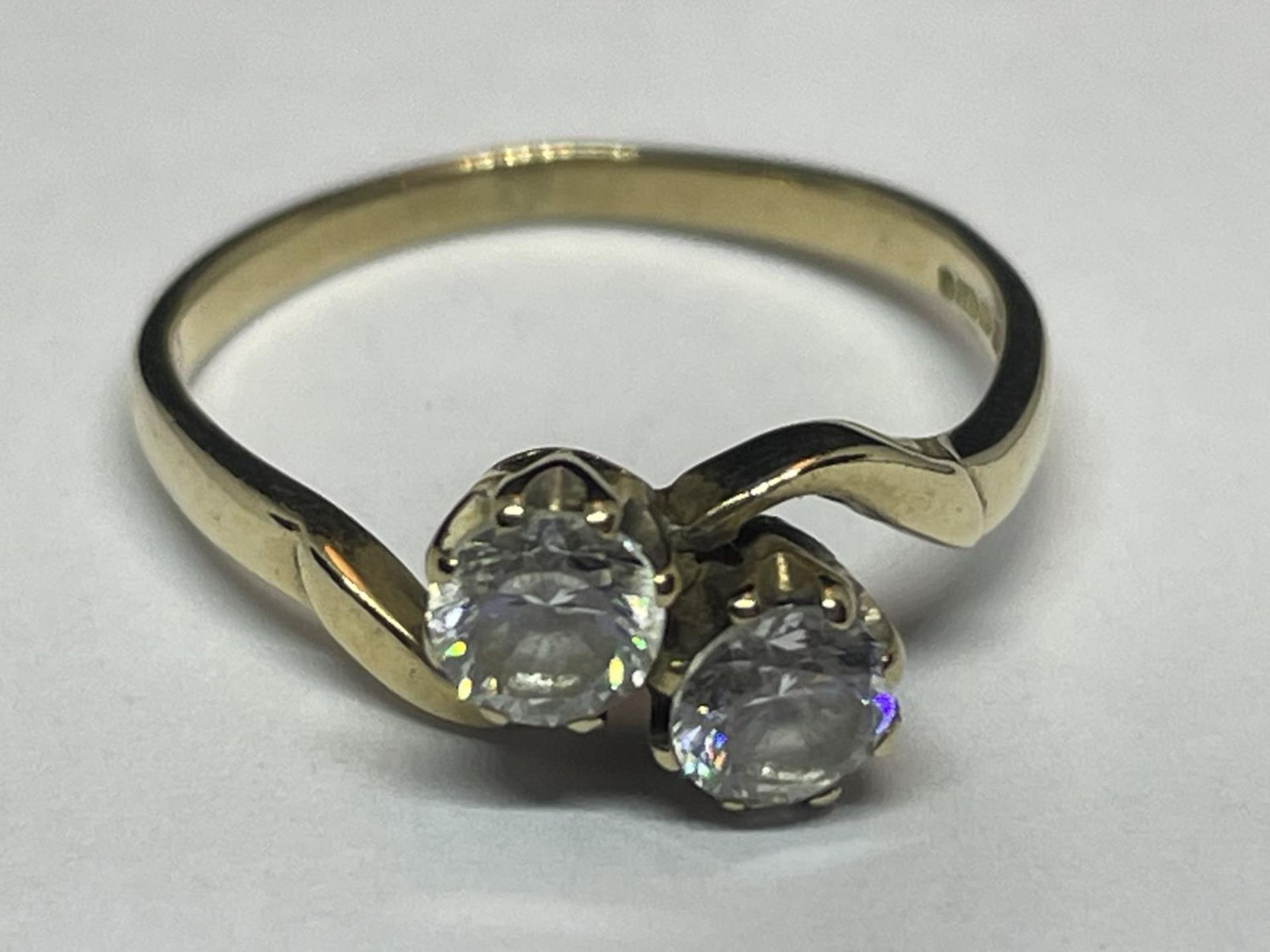 A 9 CARAT GOLD RING WITH TWO CUBIC ZIRCONIAS ON A TWIST DESIGN SIZE J