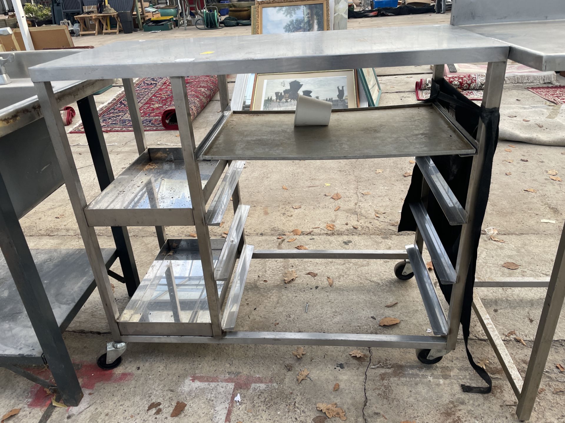 A SMALL STAINLESS STEEL FOUR WHEELED UNIT WITH TRAY STORAGE SECTIONS - Bild 2 aus 2