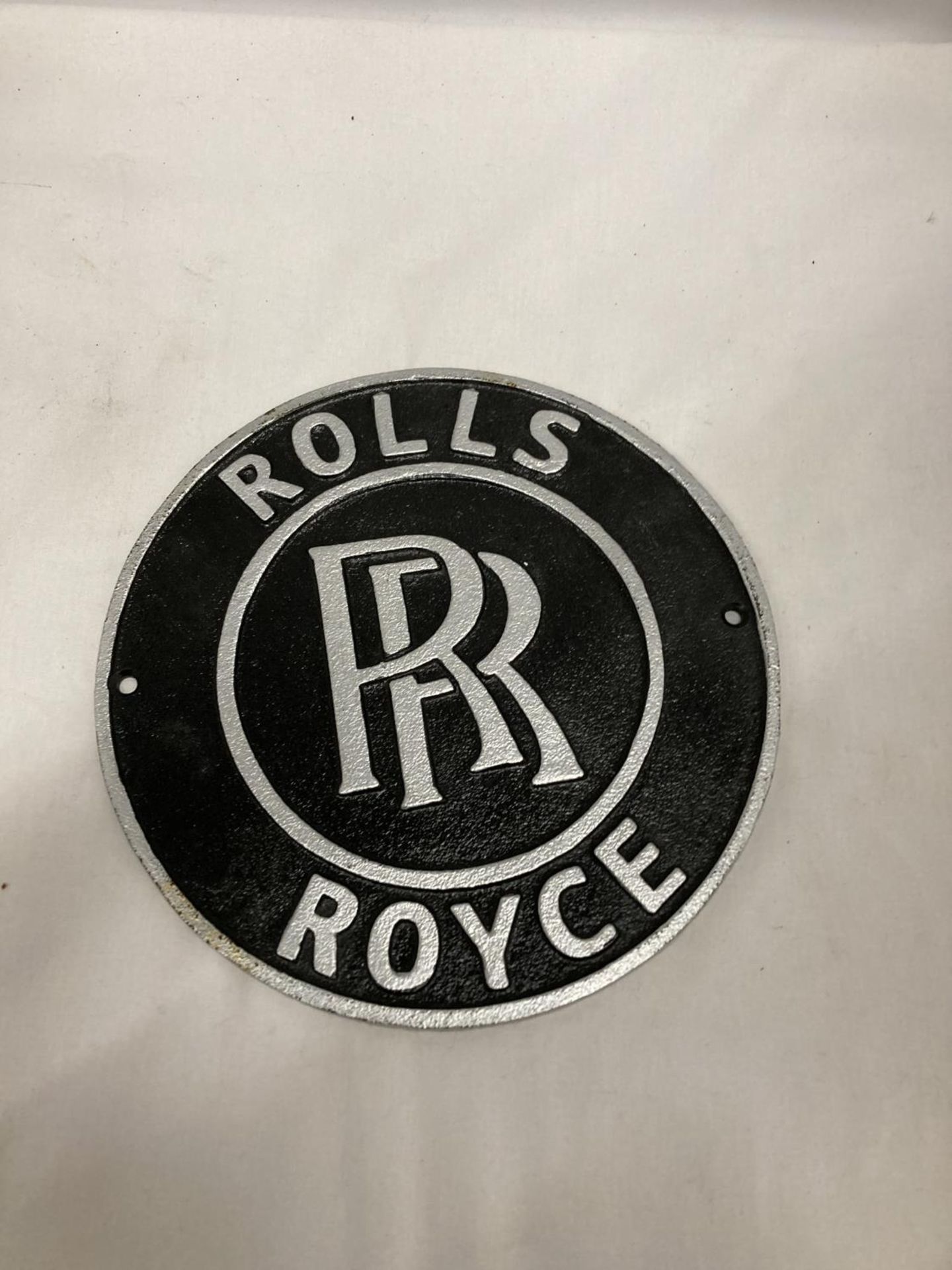 A CAST BLACK AND SILVER ROLLS ROYCE SIGN, DIAMETER 24CM