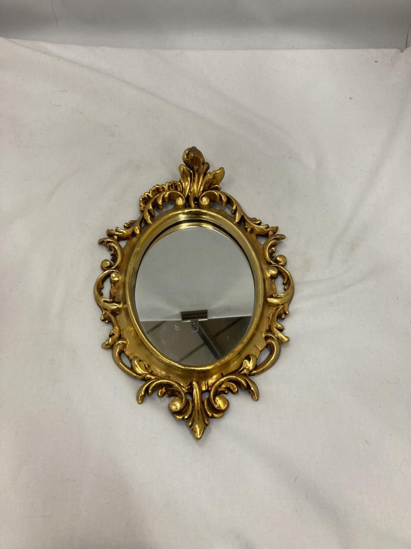 A SMALL OVAL GILT MIRROR, PLEASE NOTE THE SIZE, 19CM X 29CM