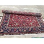 A LARGE RED PATTERNED FRINGED RUG