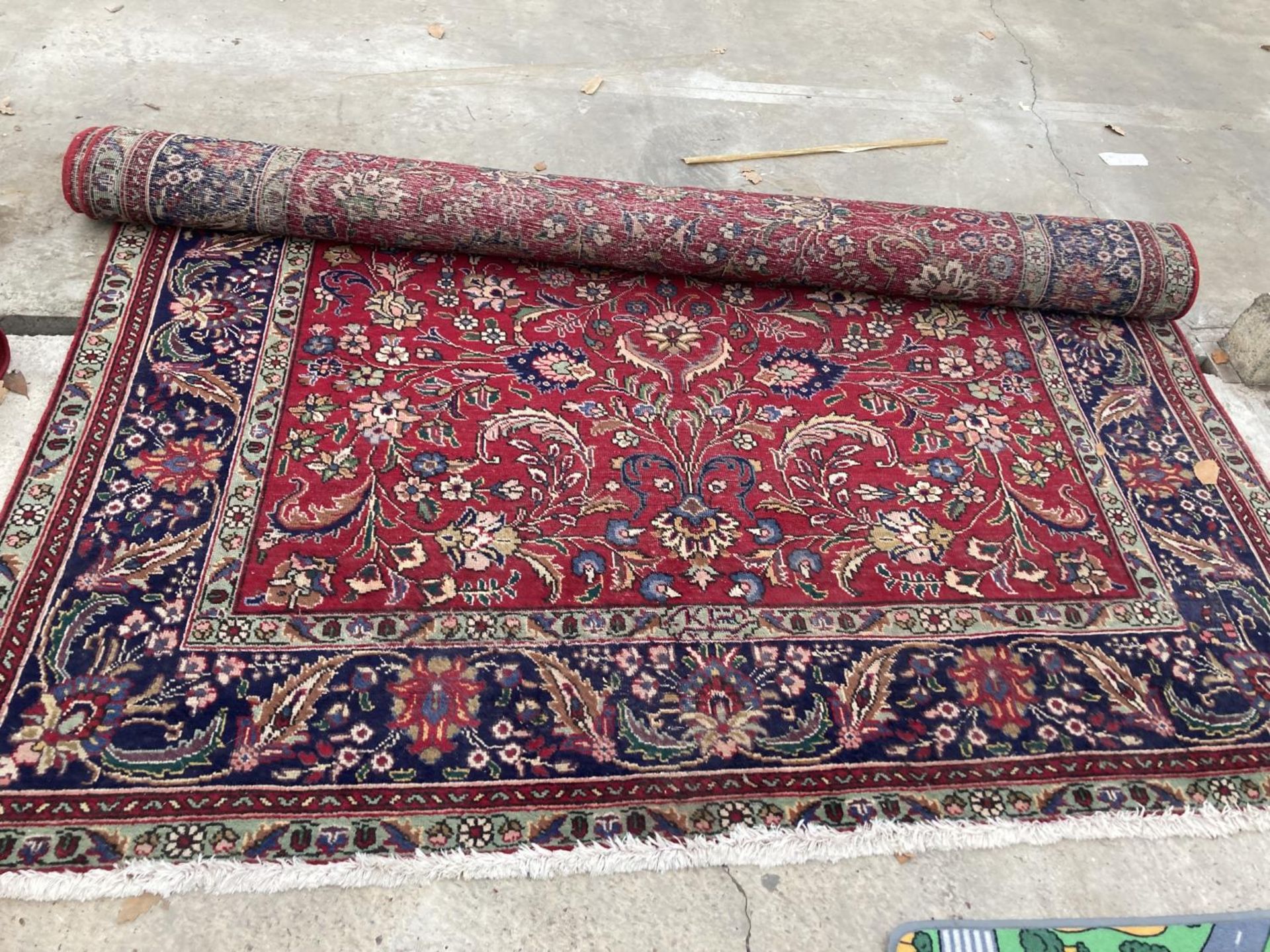 A LARGE RED PATTERNED FRINGED RUG