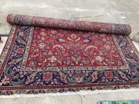 A LARGE RED PATTERNED FRINGED RUG