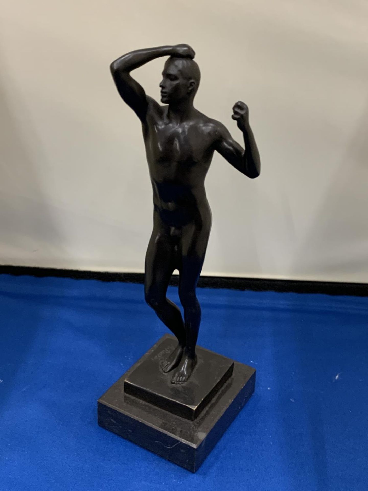 A BRONZE SCULPTURE OF A MAN ON A MARBLE BASE SIGNED