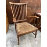 A MID 20TH CENTURY BEECH LOW RUSH SEATED FIRESIDE CHAIR WITH SWEPT ARMS AND SPINDLE BACK