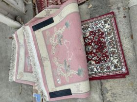 A PINK PATTERNED FRINGED RUG AND A SMALL RED PATTERNED RUG