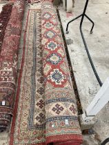 A LARGE RED PATTERNED FRINGED RUG