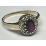 A 9 CARAT GOLD RING WITH CENTRE GARNET SURROUNDED BY CUBIC ZIRCONIAS SIZE R/S