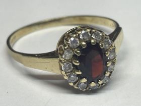 A 9 CARAT GOLD RING WITH CENTRE GARNET SURROUNDED BY CUBIC ZIRCONIAS SIZE R/S