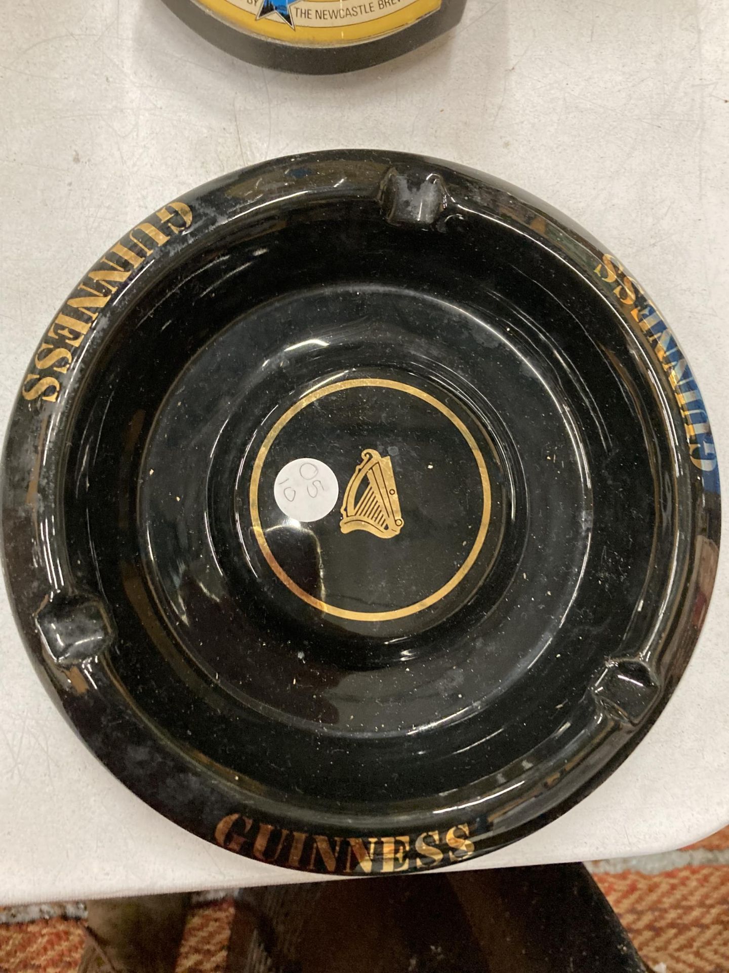 A VINTAGE WADE BLACK AND GOLD GUINNESS ASHTRAY IN VERY GOOD CONDITION