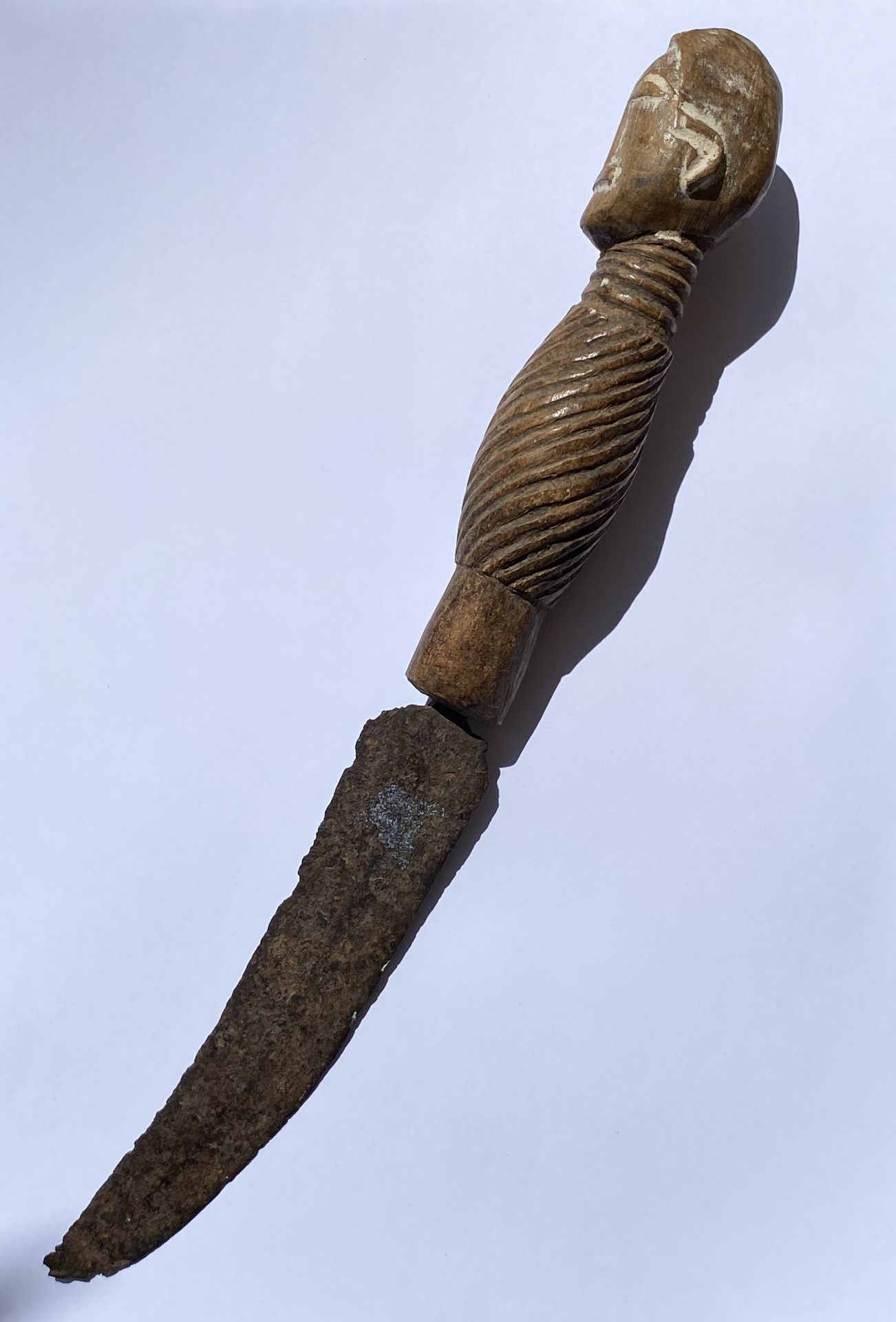 A VINTAGE AFRICAN TRIBAL CEREMONIAL DAGGER WITH CARVED WOODEN HANDLE WITH FACE DESIGN, LENGTH 28 CM