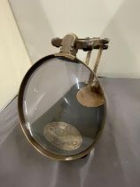 A BRASS MAGNIFYING GLASS ON A WOODEN BASE