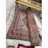 A SMALL RED AND BLUE PATTERNED FRINGED RUG