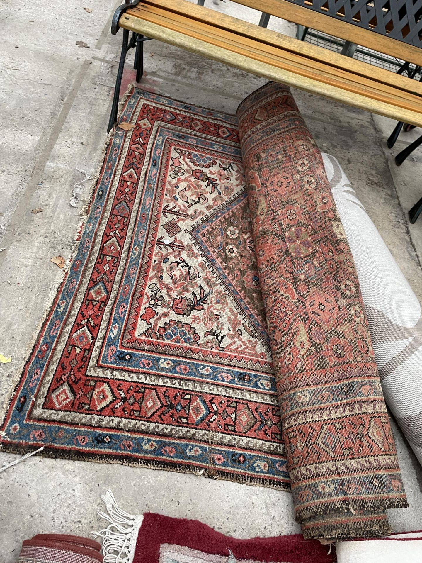 A SMALL RED AND BLUE PATTERNED FRINGED RUG