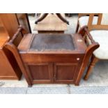 AN EARLY 20TH CENTURY PIANO STOOL ENCLOSING CUPBOARDS, LIFT-UP SEAT AND TURNED CARRYING HANDLE