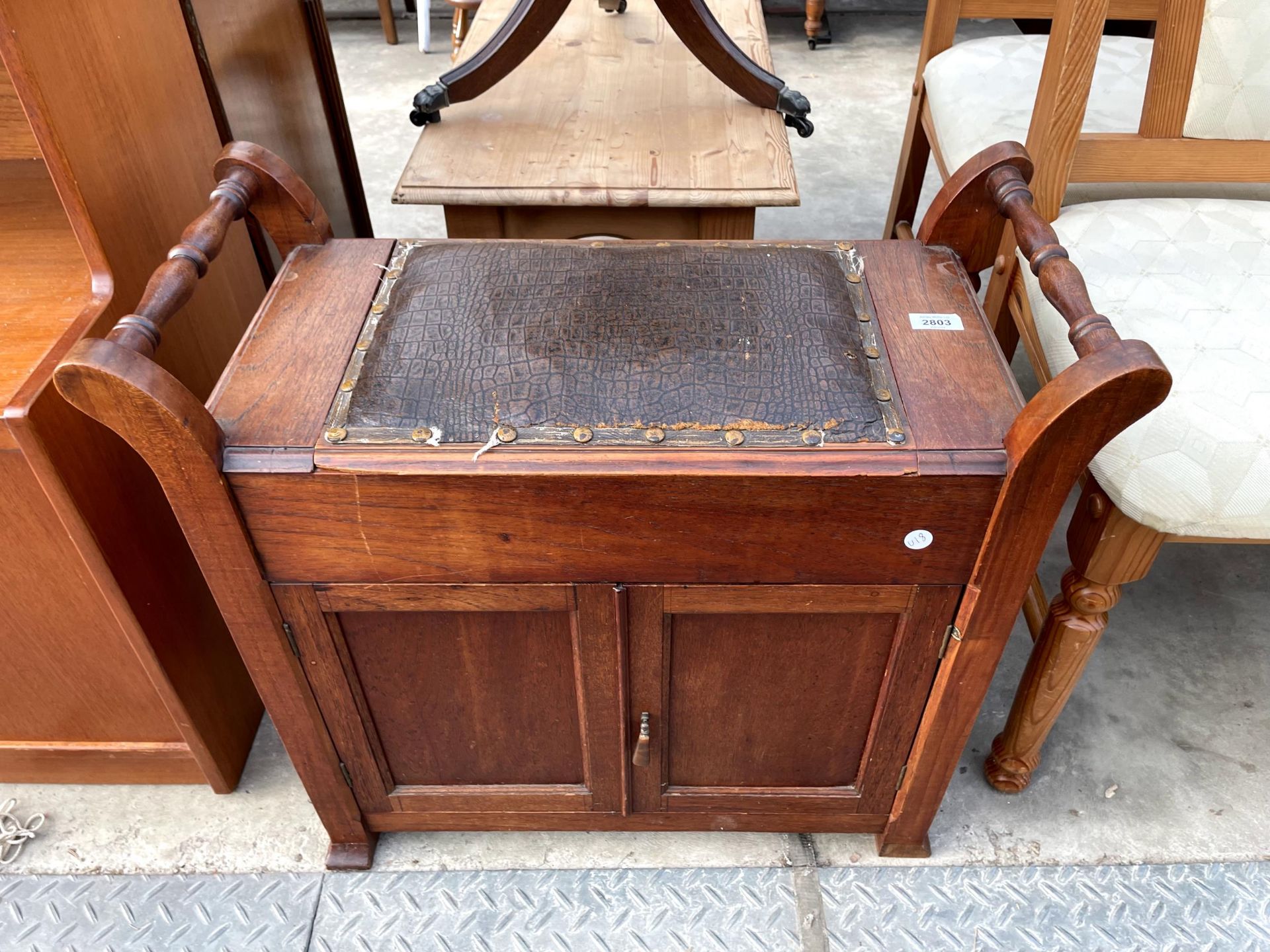 AN EARLY 20TH CENTURY PIANO STOOL ENCLOSING CUPBOARDS, LIFT-UP SEAT AND TURNED CARRYING HANDLE