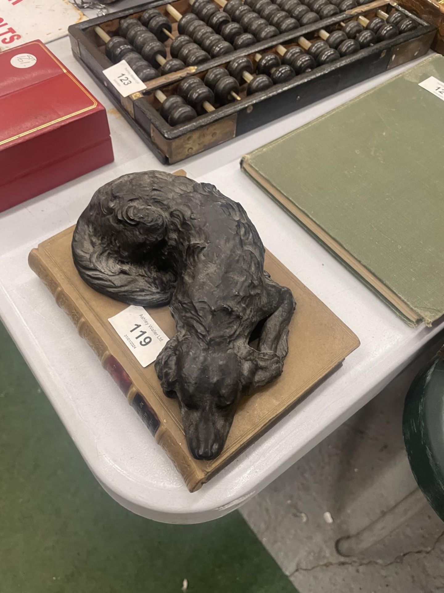 A HEAVY MODEL OF A SLEEPING DOG ON A STONEWARE BOOK, LENGTH 18CM, HEIGHT 7CM