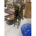 A BRONZE MODEL OF A CHILD KNEELING ON A STOOL SIGNED