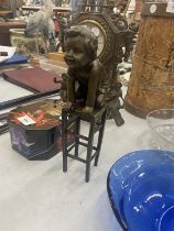 A BRONZE MODEL OF A CHILD KNEELING ON A STOOL SIGNED