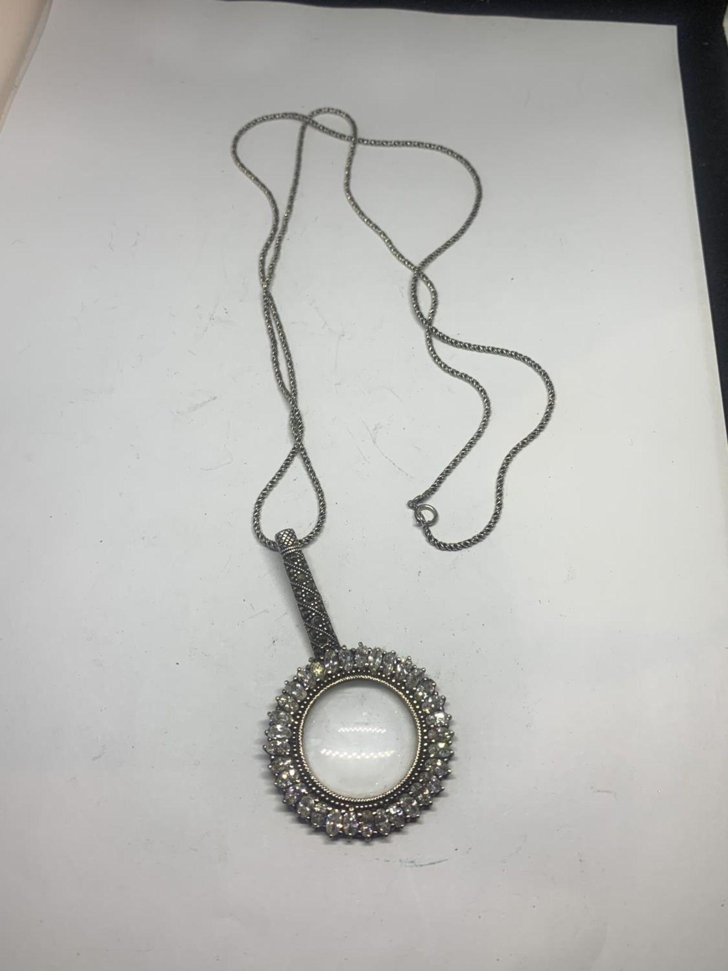 AN ORNATE SILVER MAGNIFYING GLASS ON A CHAIN WITH A PRESENTATION BOX